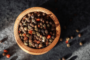 Variety of spices in a wooden bowl on a gray surface in natural light