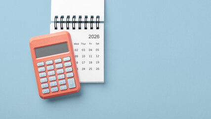 Calculator on calendar 2026 on blue background, business finance, budget planning, top view