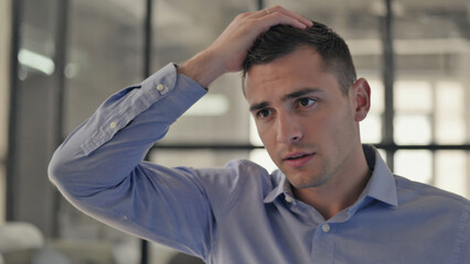 Obraz premium Frustration and Concern: A man in a shirt stands indoors, expressing a troubled state of mind. He is depicted in a medium shot, emphasizing his body language and facial expressions.