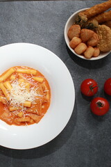 Korean Rose Tteokbokki, a creamy spicy rice cake dish topped with cheese, served with assorted...