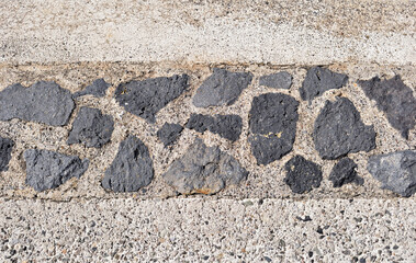 Random Black Rocks in Old Concrete Promenade  Wall in Close Up