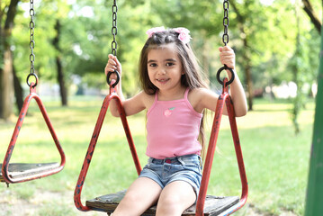 Little girl of 4 years old is playing on the playground in the park.