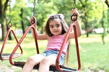 Little girl of 4 years old is playing on the playground in the park.
