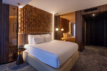Interior of a hotel room with a master bed and a decorative wooden wall