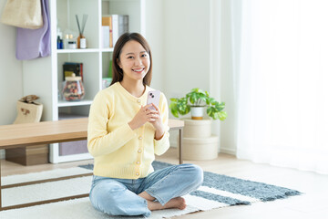 リビングでスマホを使う若い女性