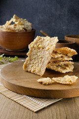 Close-up of traditional crispy tempeh chips which made from fermented soybeans served on a wooden board with a rustic setting.Suitable for culinary content, food packaging, advertising, or health food