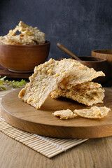 Close-up of traditional crispy tempeh chips which made from fermented soybeans served on a wooden board with a rustic setting.Suitable for culinary content, food packaging, advertising, or health food