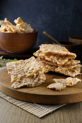 Close-up of traditional crispy tempeh chips which made from fermented soybeans served on a wooden board with a rustic setting.Suitable for culinary content, food packaging, advertising, or health food