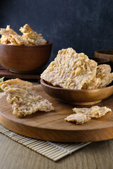 Close-up of traditional crispy tempeh chips which made from fermented soybeans served on a wooden board with a rustic setting.Suitable for culinary content, food packaging, advertising, or health food