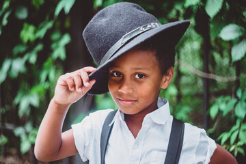 boy dressed in the style of the 20s lifts his hat holding it by the brim