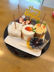 Assortment of delightful mini cakes and desserts, featuring a variety of flavors and toppings like berries and cream, presented beautifully for a birthday celebration. Perfect for special occasions.