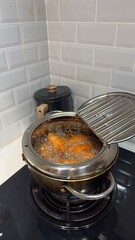 Close-up of food being deep-fried in a domestic electric deep fryer, with oil bubbling vigorously, showcasing the process of cooking crispy, golden-brown food. Ideal for home cooking concepts.