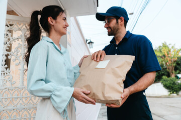 A woman receives a package from a delivery man during rush hour in front of her house.