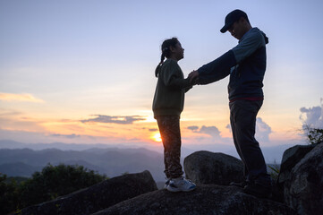 Tourists enjoy themselves on the cliff as the sun sets.