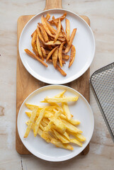 Two plates of fried french fries: one with crispy fries and one with soft, dark fries