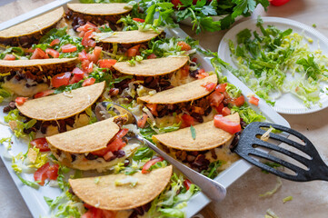 Oven baked tacos with minced meat, kidney bean, cheese filling on a baking tray fresh and homemade cooked