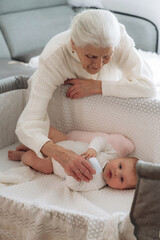 Taking care of toddler that is lying down. Grandmother with cute toddler baby at home