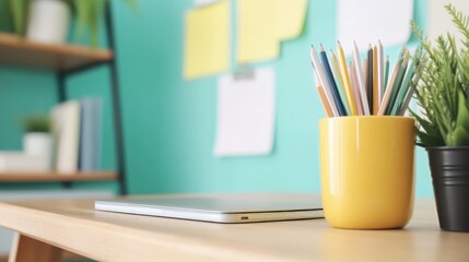 Obraz premium A home office workspace with a laptop, colored pencils, and plants