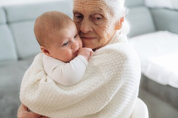Embracing the toddler. Grandmother with cute toddler baby at home