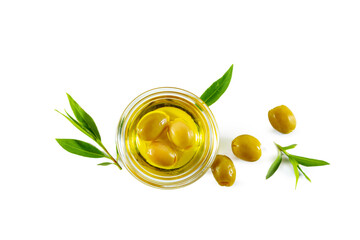 Extra virgin olive oil in a transparent bowl and green olives with leaves.