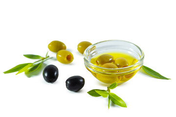 Extra virgin olive oil in a transparent bowl and black and green olives with leaves.