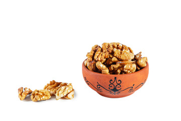 Heap of walnuts in clay bowl isolated on white background.