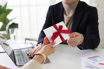 Money bonus. Employee receiving envelope with bow from boss in office, closeup
