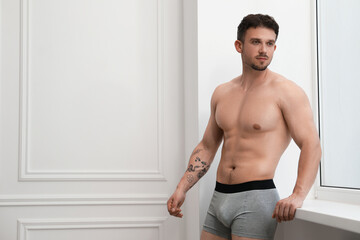 Young man in stylish light grey underwear near white wall indoors. Space for text
