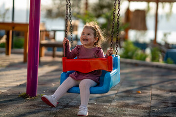 Portrait of a adorable little girl laughing when playing a swing