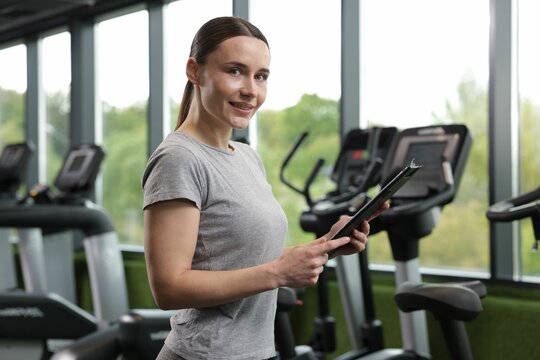 Professional personal trainer with clipboard in gym