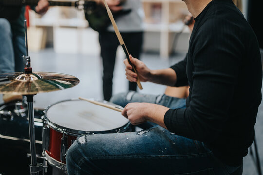 A close-up of a drummer rehearsing with a band, showcasing the vibrant energy of live music practice in a professional studio environment. Perfect for music, creativity, and teamwork concepts.