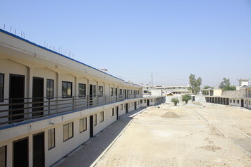 A courtyard surrounded by two-story buildings with a beige facade and black railings. 