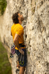 A man in a yellow shirt is climbing a rock wall