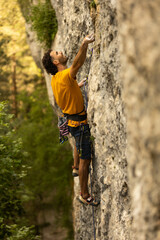 A man in a yellow shirt is climbing a rock wall