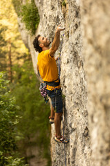 A man in a yellow shirt is climbing a rock wall