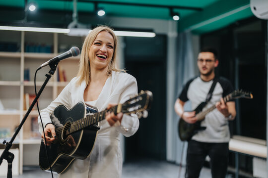 A group of musicians plays acoustic and electric guitars in a brightly lit rehearsal studio. The scene captures the enthusiasm and collaboration of a band practicing their musical performance.