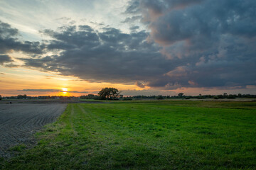 Evening clouds from sunset over the meadow next to the field