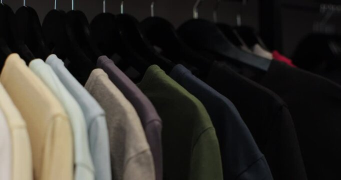 Woman in the shop looks through the male clothes, which are hanging on the racks. Home closet or wardrobe.