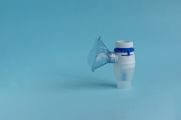 A nebulizer with a steam mask on a blue background on the left side is a place for text