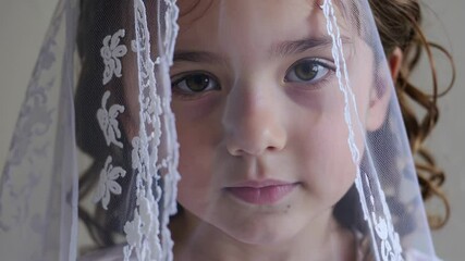 Young girl wearing delicate white lace veil, revealing contemplative expression during sacred religious milestone ceremony, capturing youthful innocence and spiritual significance