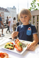 Family with children, having lunch in a restaurant in Coppenhagen, eating local fish and lobster thermidor with salad and fries