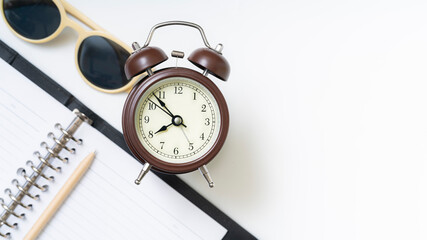 classic alarm clock and sun glasses on stacked books illustrating time management and education focus
