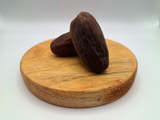 Date palm fruit on a on a round wooden board. Date palm fruits, or simply dates, are the oval-shaped, sweet, edible fruit of the date palm tree (Phoenix dactylifera)