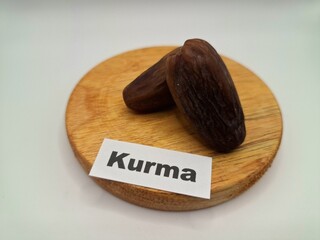 Date palm fruit on a on a round wooden board. Date palm fruits, or simply dates, are the oval-shaped, sweet, edible fruit of the date palm tree (Phoenix dactylifera)