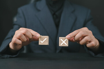 Businesswoman select correct sign mark between Cross mark which print screen on wooden cube block...