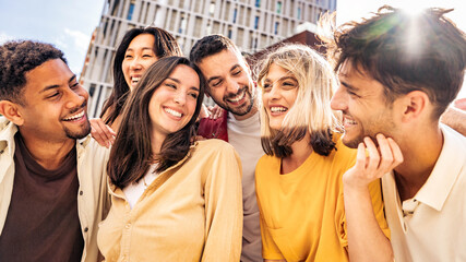 Multiracial friends having fun on citu street  - Group of young people laughing together outdoors - Friendship concept with guys and girls hanging outside on a sunny day
