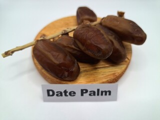 Date palm fruit on a on a round wooden board. Date palm fruits, or simply dates, are the...