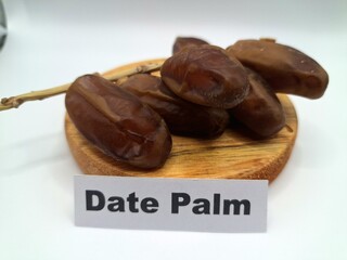 Date palm fruit on a on a round wooden board. Date palm fruits, or simply dates, are the...