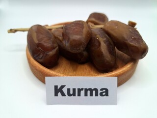 Date palm fruit on a small wooden plate. Date palm fruits, or simply dates, are the oval-shaped, sweet, edible fruit of the date palm tree (Phoenix dactylifera)