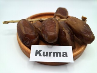 Date palm fruit on a small wooden plate. Date palm fruits, or simply dates, are the oval-shaped, sweet, edible fruit of the date palm tree (Phoenix dactylifera)
